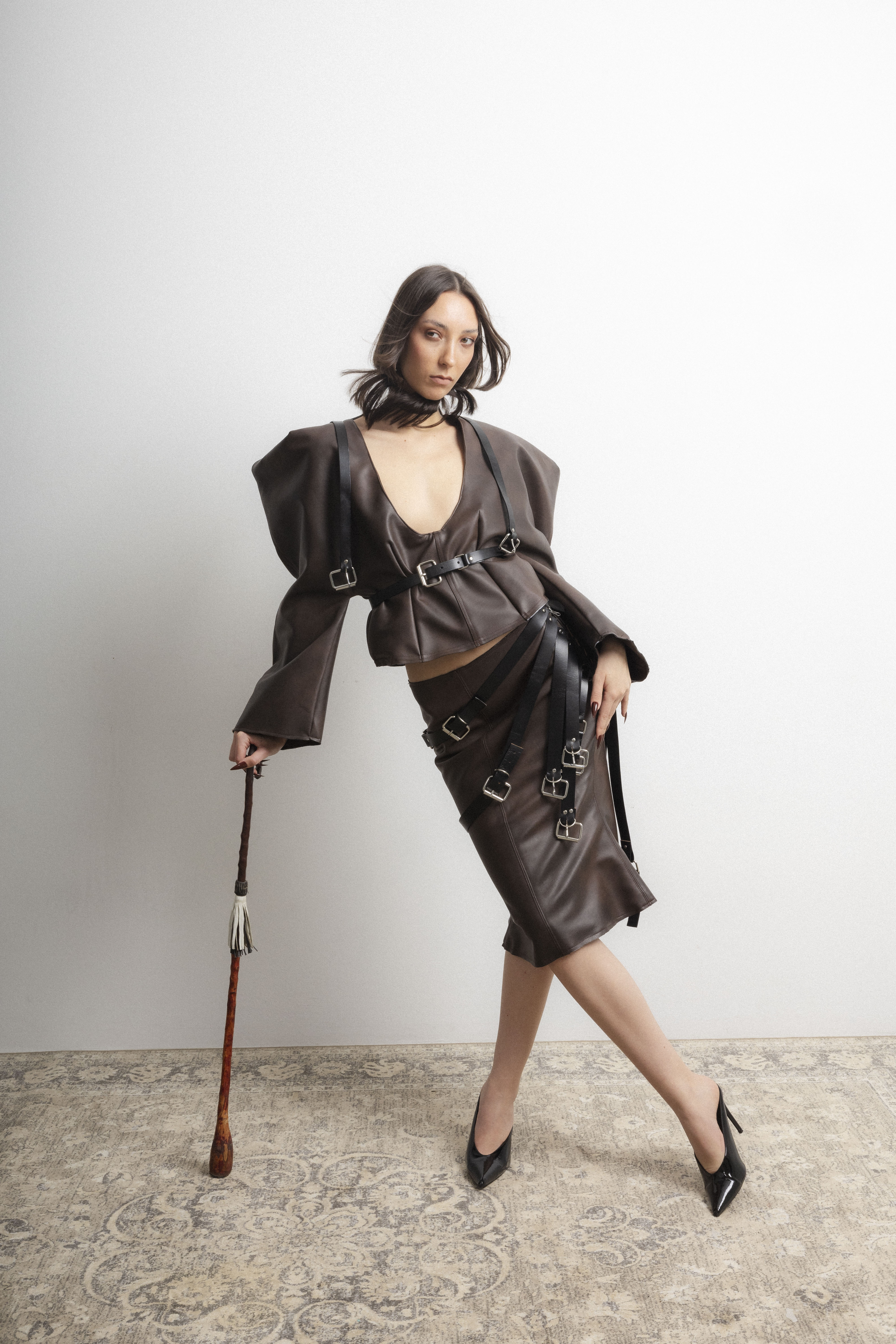 Dos modelos colocadas una detrás de la otra, con siluetas estructuradas y volúmenes dramáticos en una editorial de moda de inspiración ecuestre.